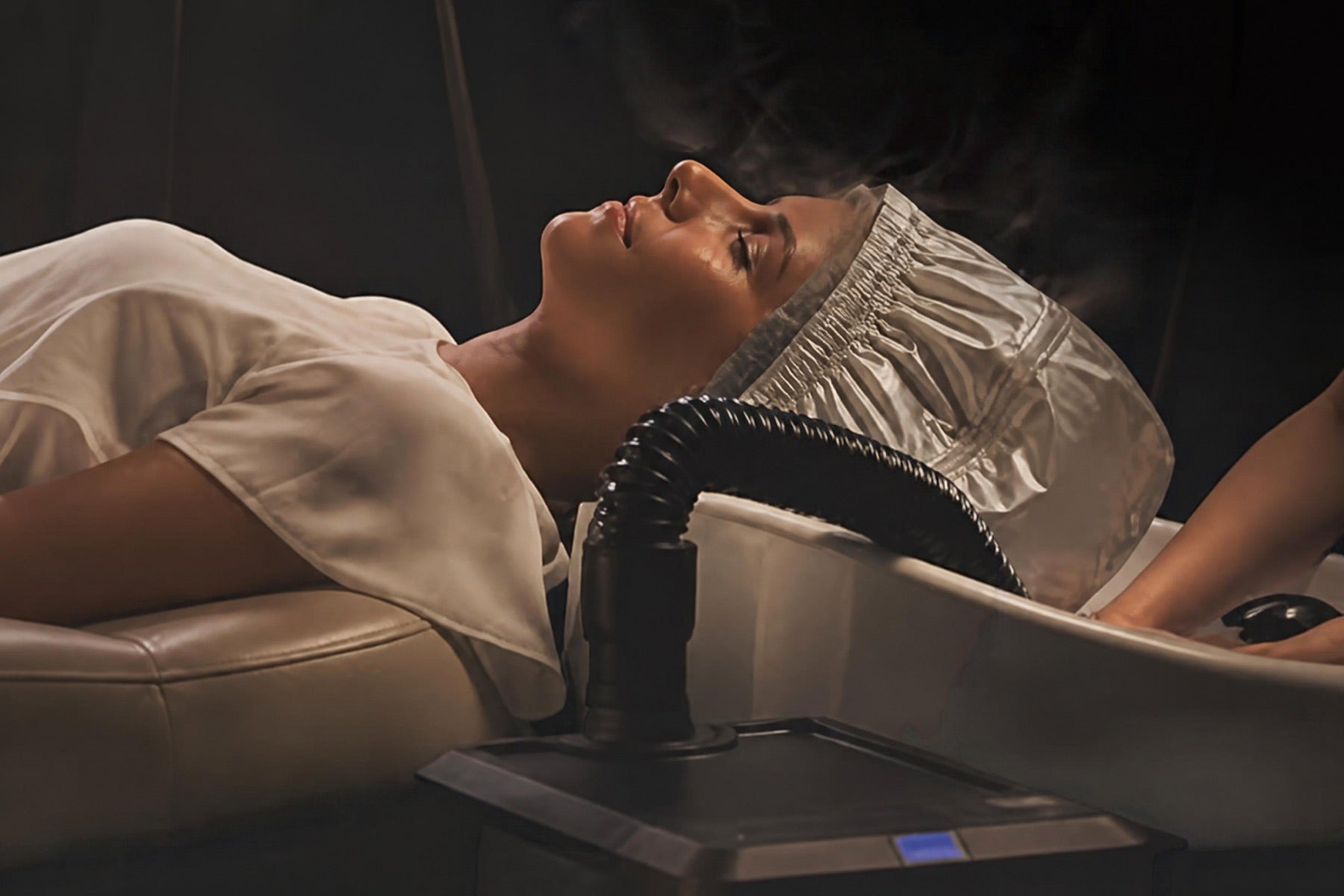 Cliente allongée sous le bonnet de vapeur du Japanese Head Spa, les yeux fermés